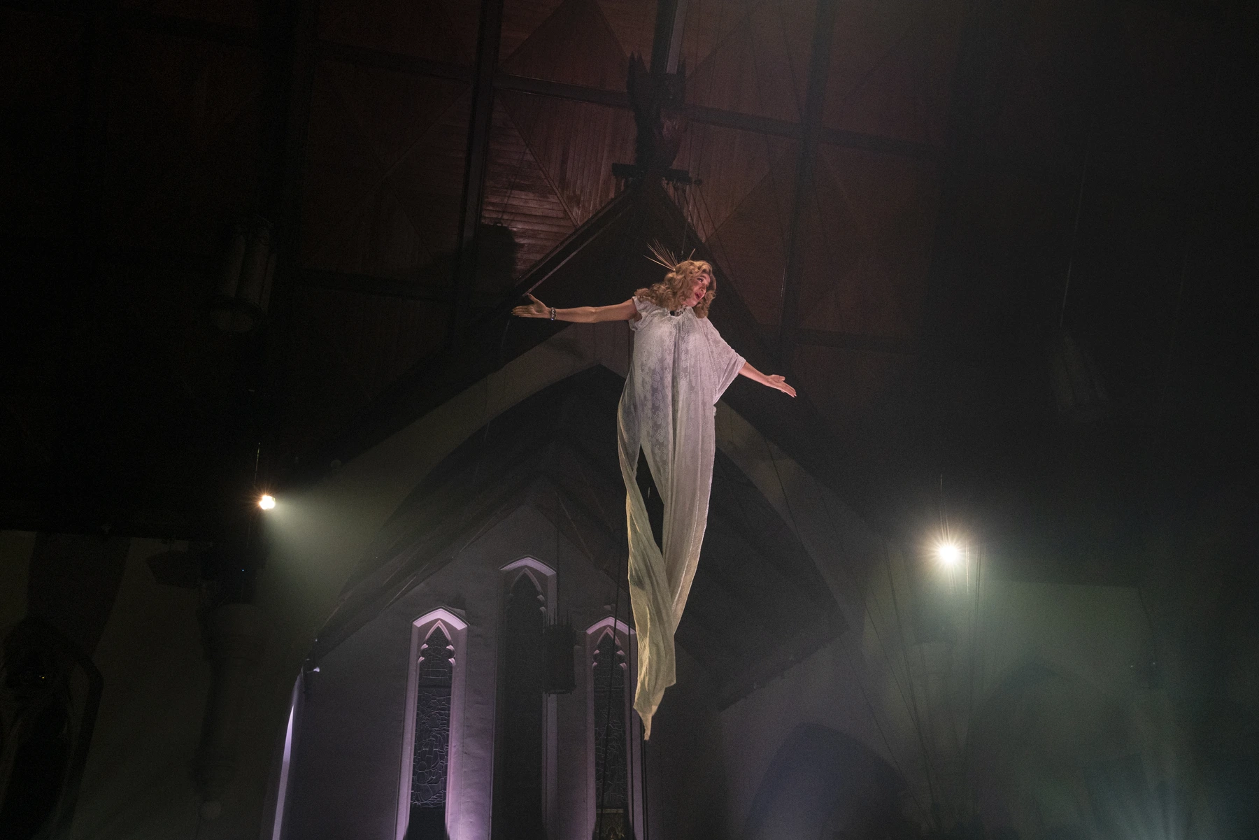 La figure en robe blanche s’élève dans la salle du spectacle Envol.